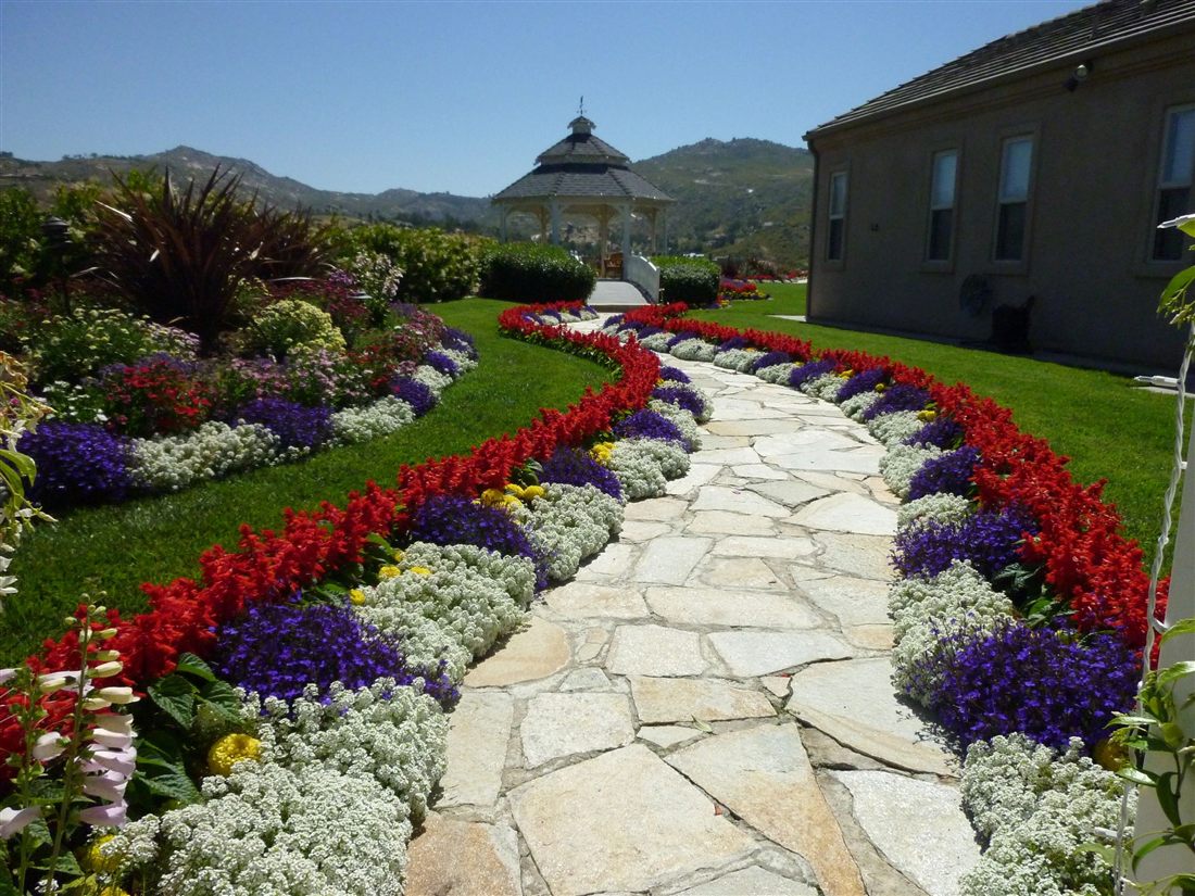 Flagstone walkway through colorful flower beds and healthy lawn